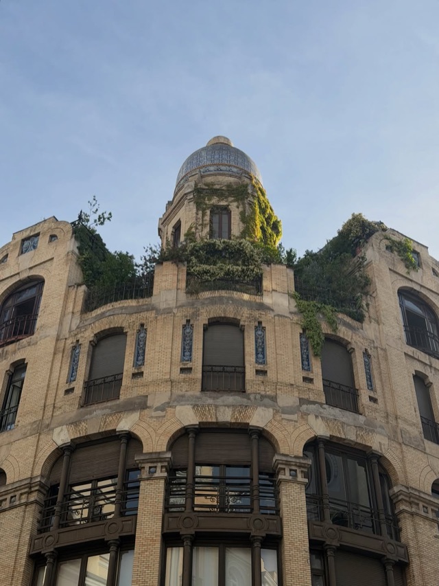 Overgrown art nouveau facade with a tiled dome in evening light